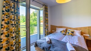 A bedroom with a bed, a nightstand, a lamp, and a view of the outdoors. - Aparthotel pod Stokiem (Szczyrk)