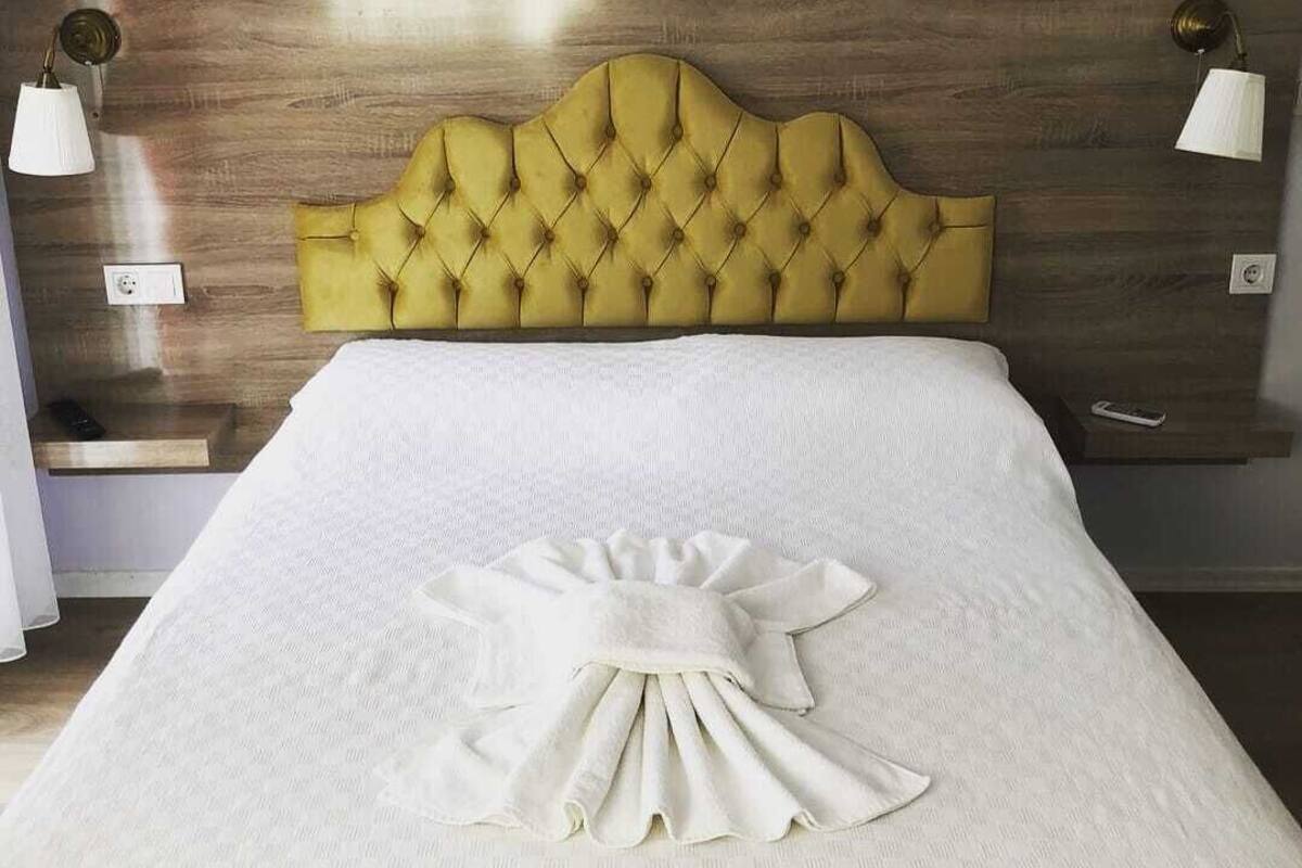 A neatly made bed with a tufted headboard, a white bedspread, and a decorative pillow arrangement.