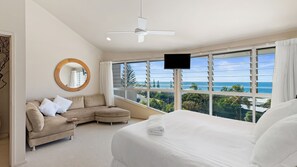 Relax in a serene ocean-view room with a large bed, sofa, and flat-screen TV.