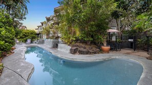 Relax by the serene pool surrounded by lush greenery and modern architecture.
