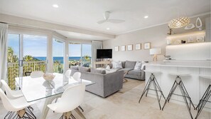 Relax in this stylish living area with a large glass table, comfortable sofa, and flat-screen TV.