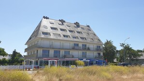 A multi-story building with balconies, a church with a tall steeple, and a clear blue sky. - Beautiful duplex with sea view balcony at Le Cabellou in Concarneau  (Concarneau)
