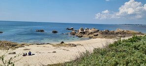 A beach with clear blue water, large rocks, and a few people sitting on the sand. - Beautiful duplex with sea view balcony at Le Cabellou in Concarneau  (Concarneau)