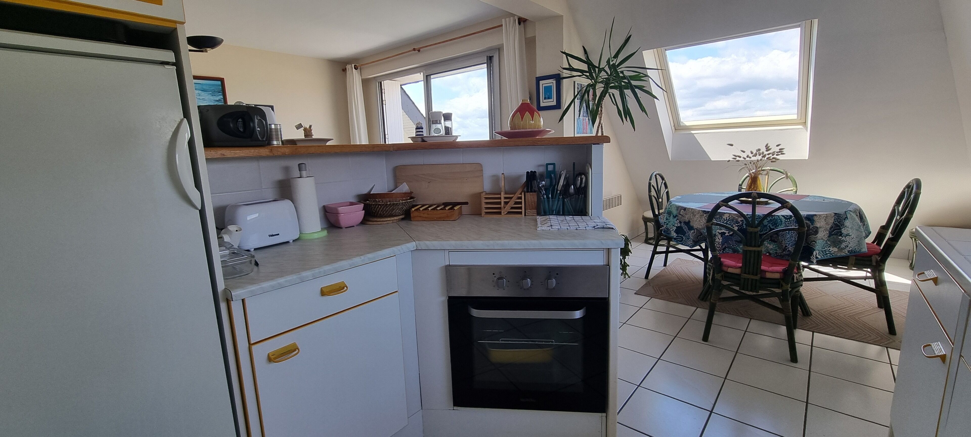 Una cocina compacta con horno integrado, una mesa de comedor con sillas y una ventana que proporciona luz natural.