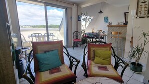 A balcony with two chairs, a dining table with chairs, and a potted plant. - Beautiful duplex with sea view balcony at Le Cabellou in Concarneau  (Concarneau)