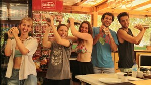 En grupp människor i en avslappnad miljö med en bardisk, en menytavla och en skylt med texten ”TADIM”.