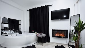 A modern bathroom with a freestanding bathtub, a large mirror, a flat-screen TV, and a fireplace. - Lux: Jacuzzi Semineu Pat Rotund Oglinda Tavan (Craiova, Preajba)