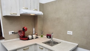 A compact kitchen with white cabinetry, a black trash bin, and a sink. - Lux: Jacuzzi Semineu Pat Rotund Oglinda Tavan (Craiova, Preajba)