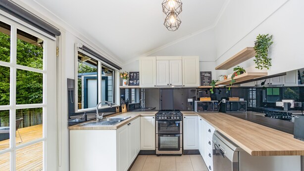 A modern kitchen with white cabinetry, a built-in oven, and a wooden countertop. - Sunshine Cottage with private garden, Katoomba (Katoomba)