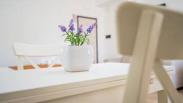 A white table with a white vase containing purple flowers.