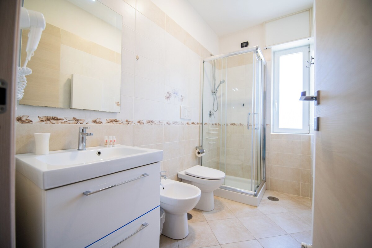 Un baño moderno con cabina de ducha de vidrio, un lavamanos blanco y un inodoro.