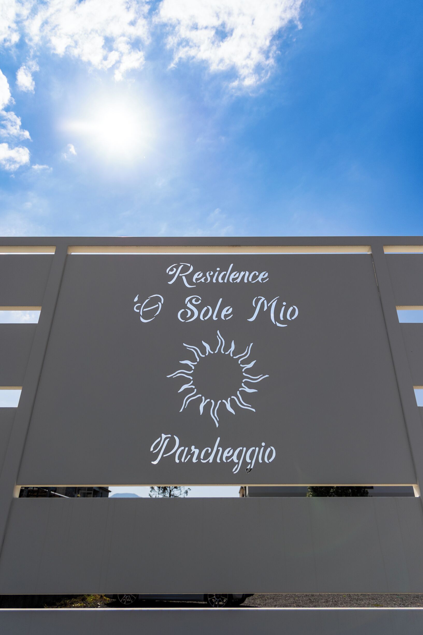 A building facade with the text "Residence O Sole Mio Parcheggio" and a sun design.