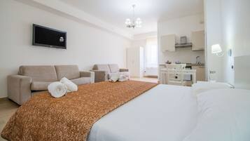 Une chambre d’hôtel comprenant un lit, deux canapés, une télévision, un bureau et une kitchenette.
