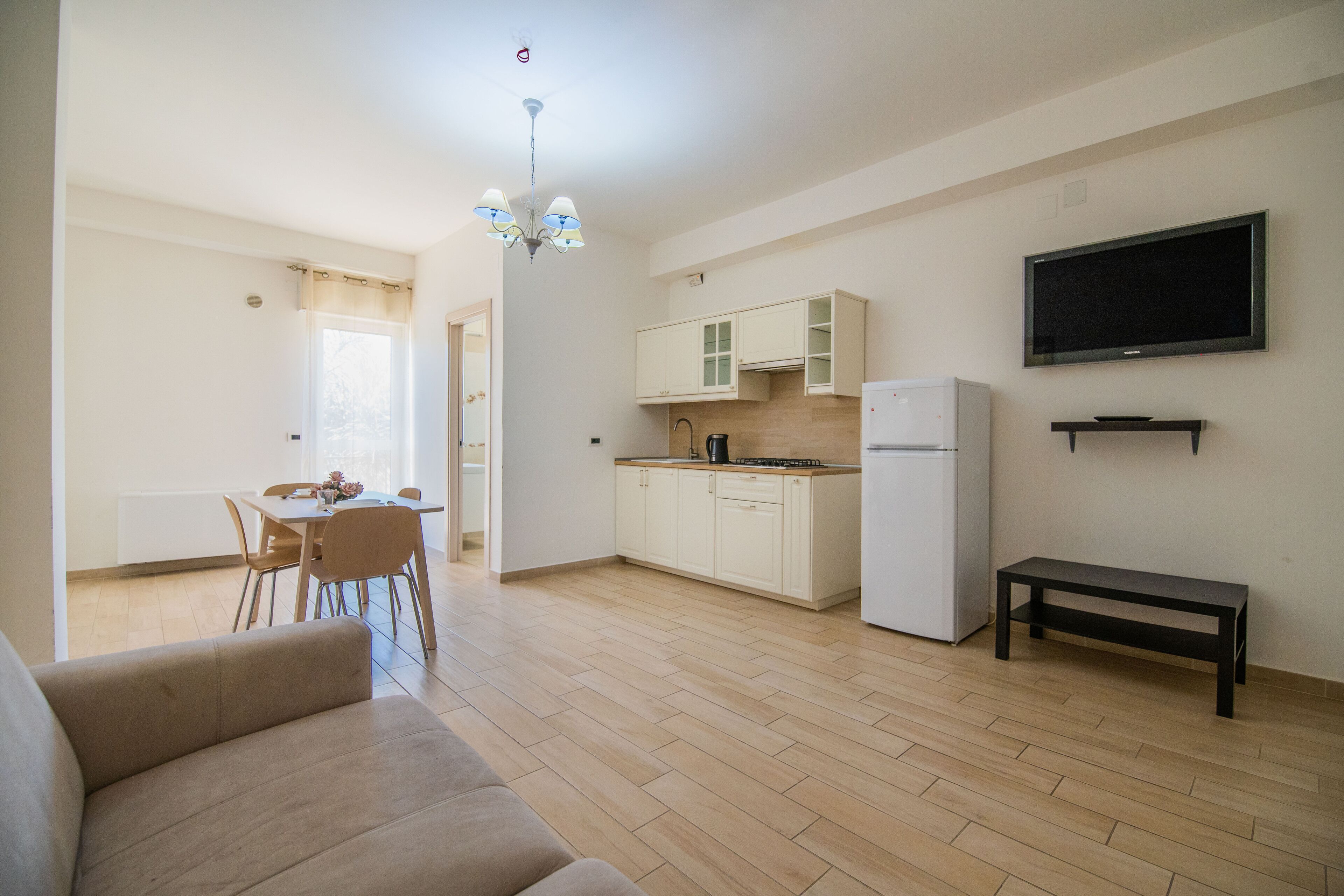 Un appartement moderne comprenant un salon, un coin repas, une cuisine et un téléviseur fixé au mur.