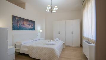 A bedroom with a bed, a nightstand, a wardrobe, a painting on the wall, and a ceiling light.