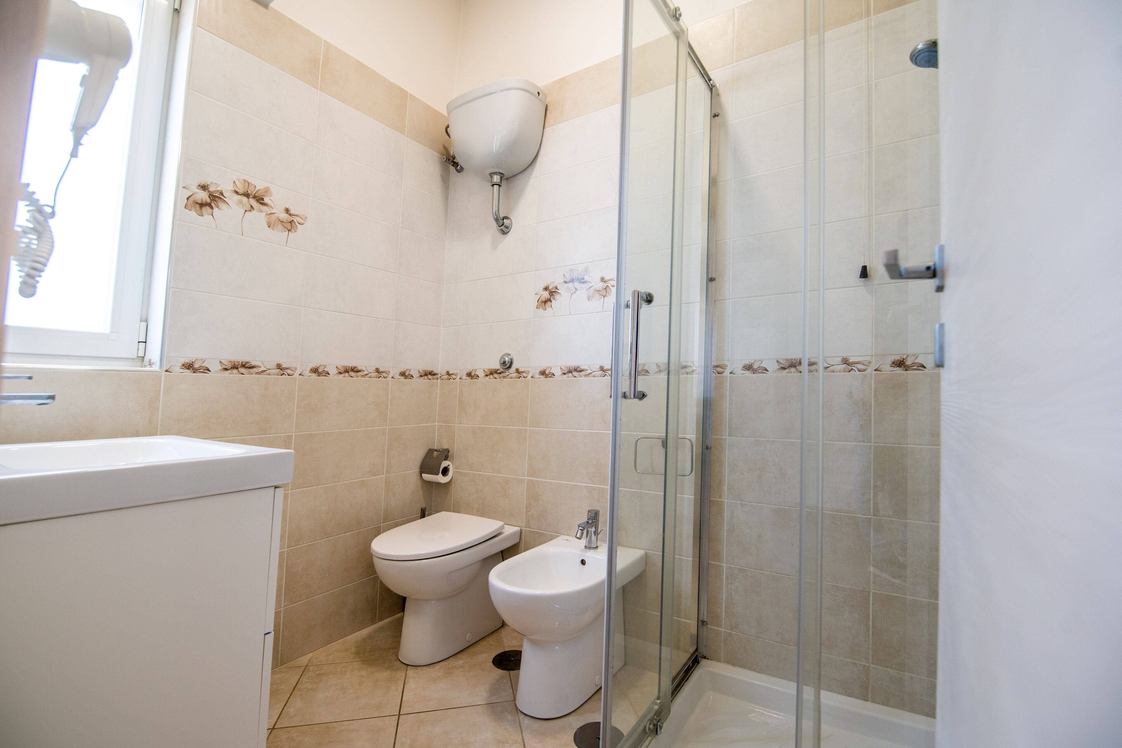 A bathroom with a toilet, bidet, and glass-enclosed shower.
