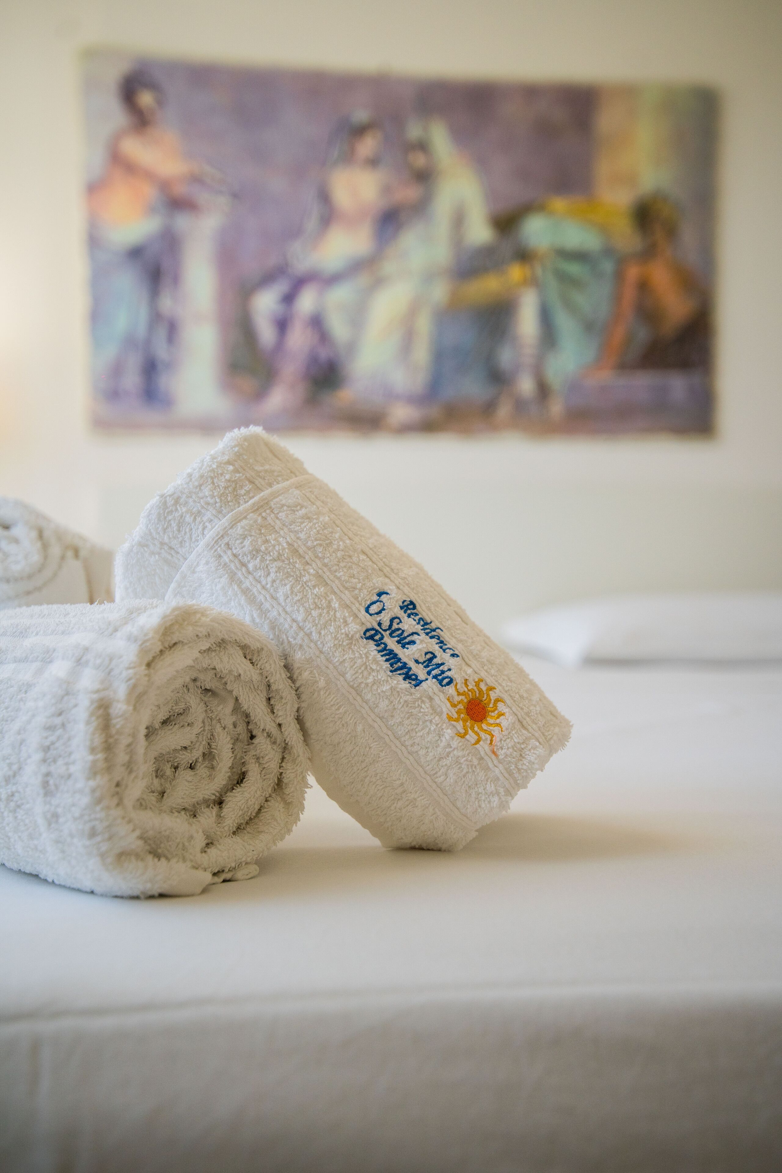 A neatly folded towel with a sun emblem and text on a bed.