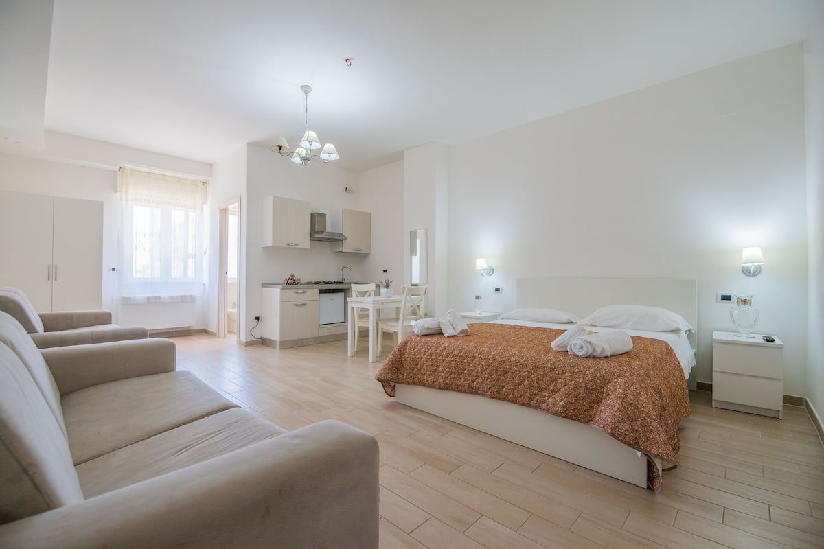 Ein modernes Hotelzimmer mit Bett, einer Sitzecke, einem Essbereich und einer Küchenzeile.