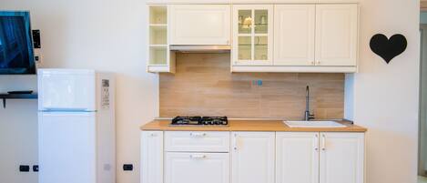 A compact kitchen with white cabinets, a built-in stove, and a sink.