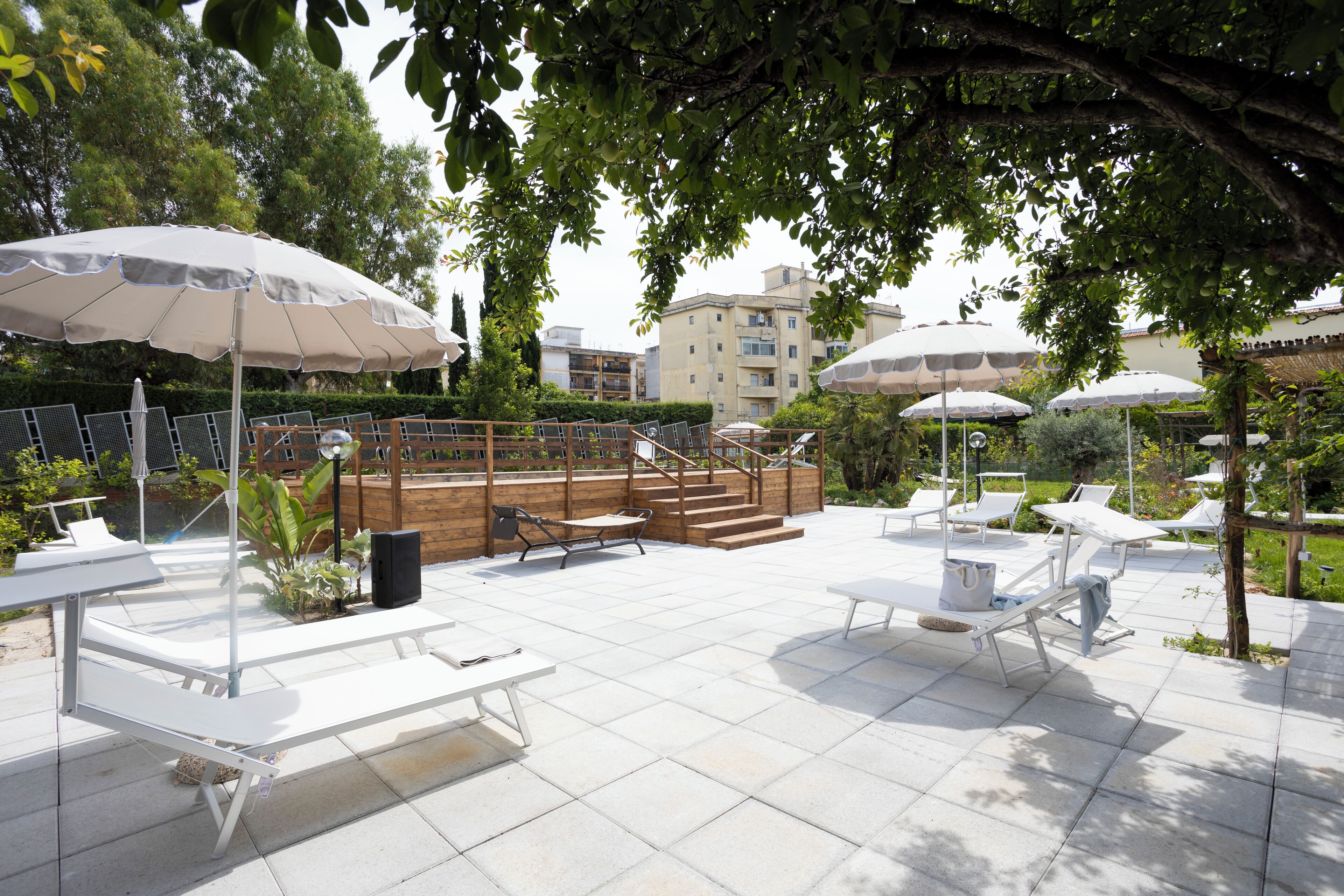 An outdoor patio area with white lounge chairs, umbrellas, and a wooden deck.