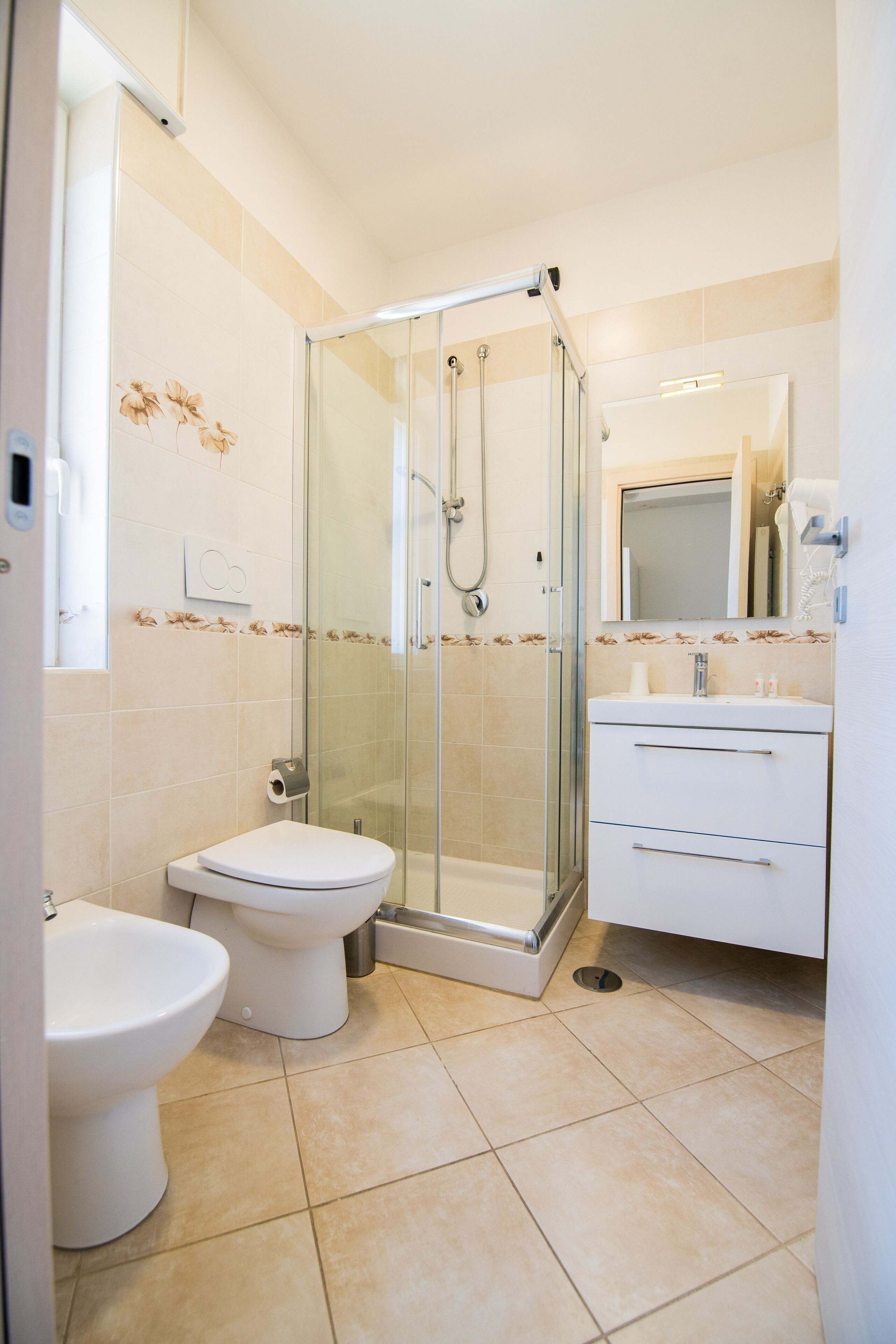 A modern bathroom with a glass-enclosed shower, a toilet, and a sink with a mirror above it.