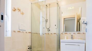A modern bathroom with a glass-enclosed shower, a toilet, and a sink with a mirror above it.