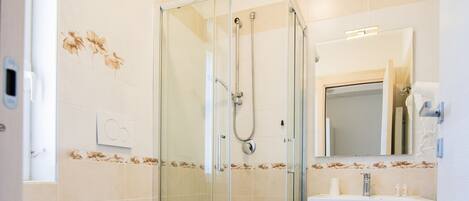 Un baño moderno con ducha de vidrio, inodoro y lavamanos con espejo.