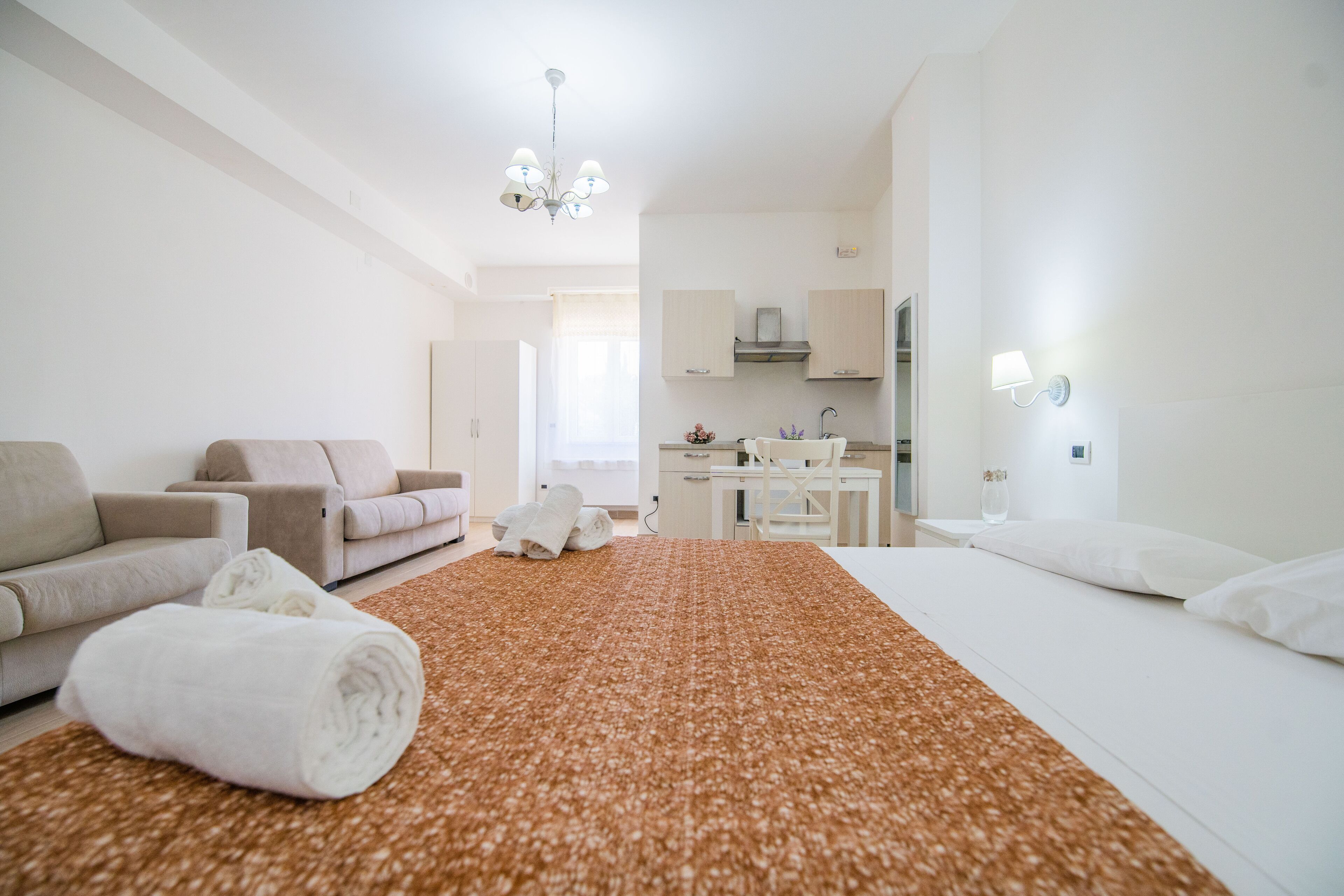 A hotel room with a bed, a sofa, a desk, and a kitchenette.