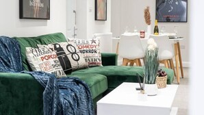 A modern living room with a green sofa, white coffee table, and framed movie posters on the walls. - Livestay - 2 Bed Hollywood Movie Themed Apt (Barnet)