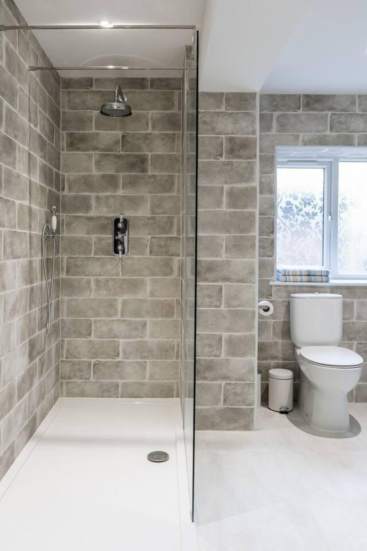 Baño con ducha, inodoro y ventana.