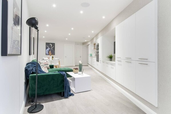 Un salon moderne avec un canapé vert, une table basse blanche et un lampadaire.
