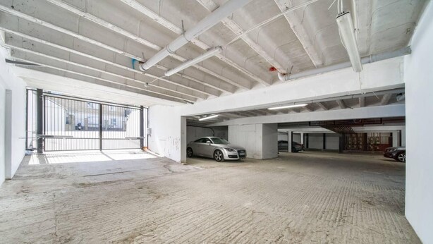 An empty parking garage with concrete floors and white walls. - Livestay - 2 Bed Hollywood Movie Themed Apt (Barnet)