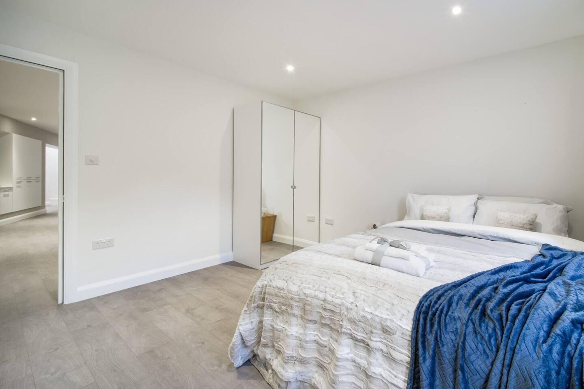A bedroom with a bed, a wardrobe, and a mirror.
