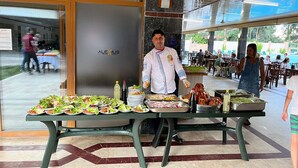 A buffet setup with various dishes and a person serving food. - Alexius Beach Hotel (Kemer)