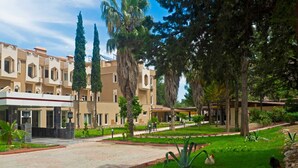 A hotel courtyard with a paved walkway, palm trees, and a well-maintained lawn. - Alexius Beach Hotel (Kemer)