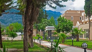 A residential area with modern buildings, a paved road, and a mountain backdrop. - Alexius Beach Hotel (Kemer)