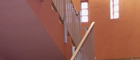 A staircase with wooden railings and a red wall.