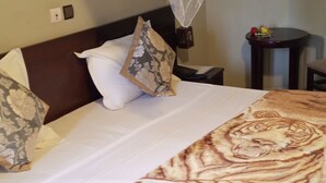 Un lit avec une couvre-lit à motifs, une tête de lit et une table de chevet avec une lampe.