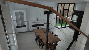 Een moderne keuken met een houten eettafel, zwarte stoelen en een trap met een houten leuning.
