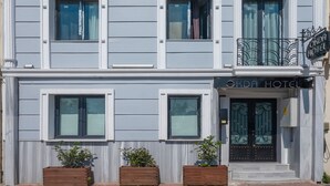 Un hotel de varios pisos con fachada simétrica, ventanas amplias y un balcón con barandilla decorativa.