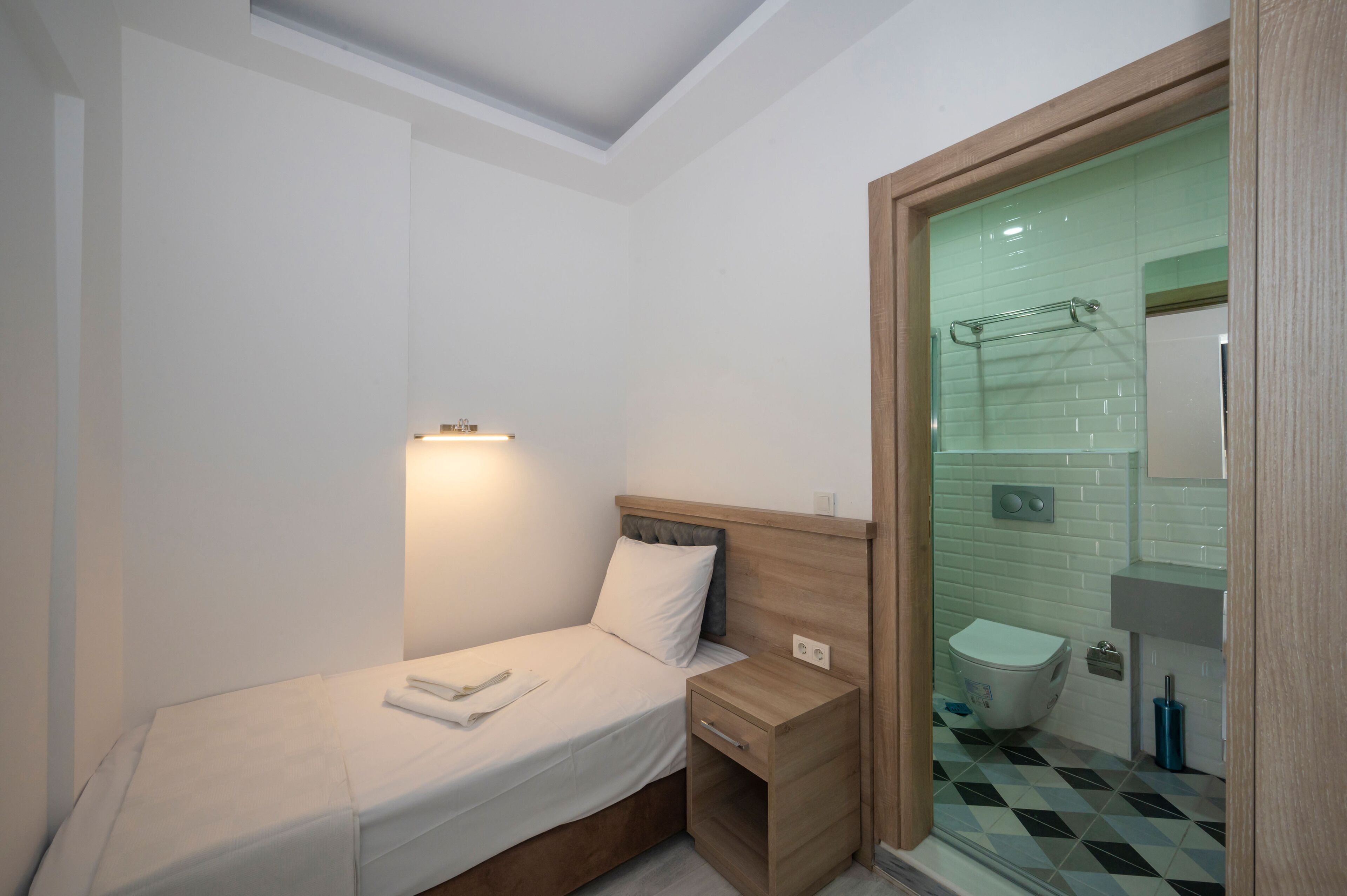 Een kleine, moderne slaapkamer met een enkel bed, een nachtkastje en een inbouwkast.