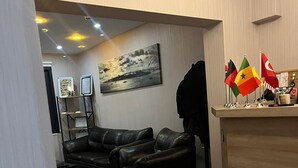 Una sala de estar con un sofá de cuero negro, un aparador de madera y un cuadro en la pared.