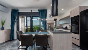 Una cocina moderna con una isla central, electrodomésticos negros y vistas al exterior.