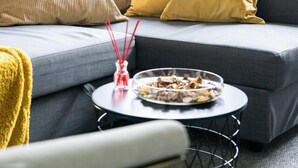 A modern living room with a grey sofa, yellow cushions, a round coffee table with a glass bowl and red candle. - Livestay - One Bed Apt, Free Parking, Sleeps 4 (Slough)