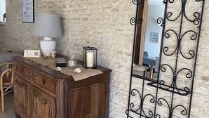 Una habitación rústica con un aparador de madera, un espejo con marco metálico decorativo y una pared de piedra.