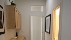 A hallway with a wooden cabinet, a framed picture, and a door leading to another room. - Pet-Friendly Vegas House w/ EV Charger & Parking (Las Vegas)