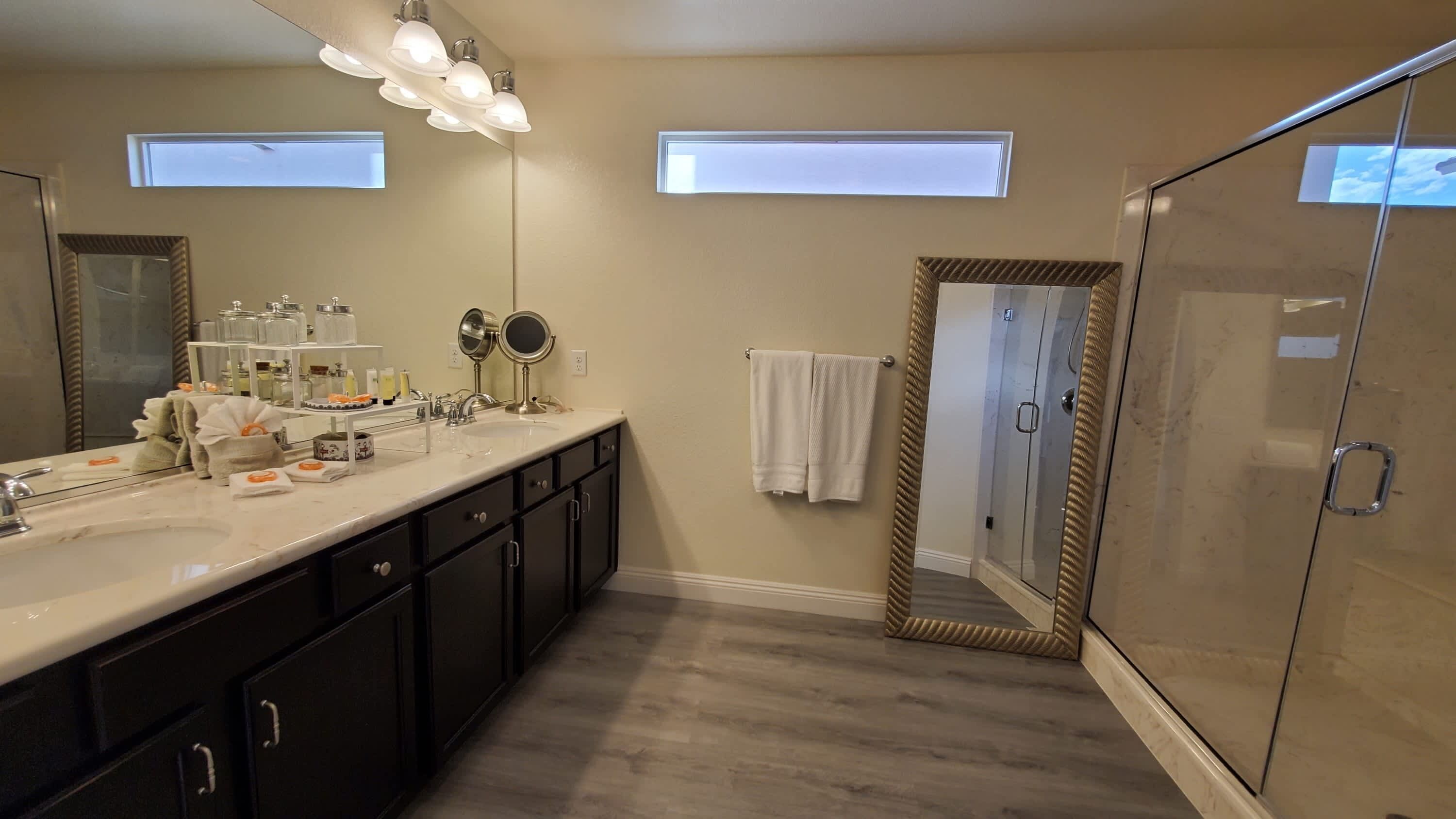 Un baño moderno con un tocador espacioso, cabina de ducha de vidrio y tragaluces.