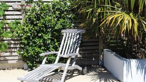 A wooden Adirondack chair with a metal frame, positioned on a concrete surface.
