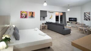 Une chambre d’hôtel moderne équipée d’un lit, d’un canapé, d’un coin repas et d’une télévision.