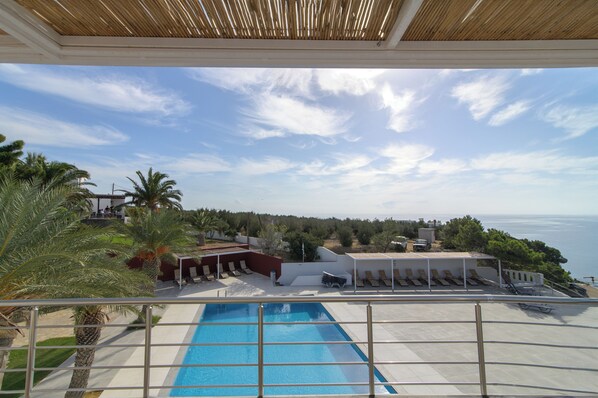 A pool area with a view of the sea, lounge chairs, and a covered seating area. - Porto Belissario (Ierapetra)